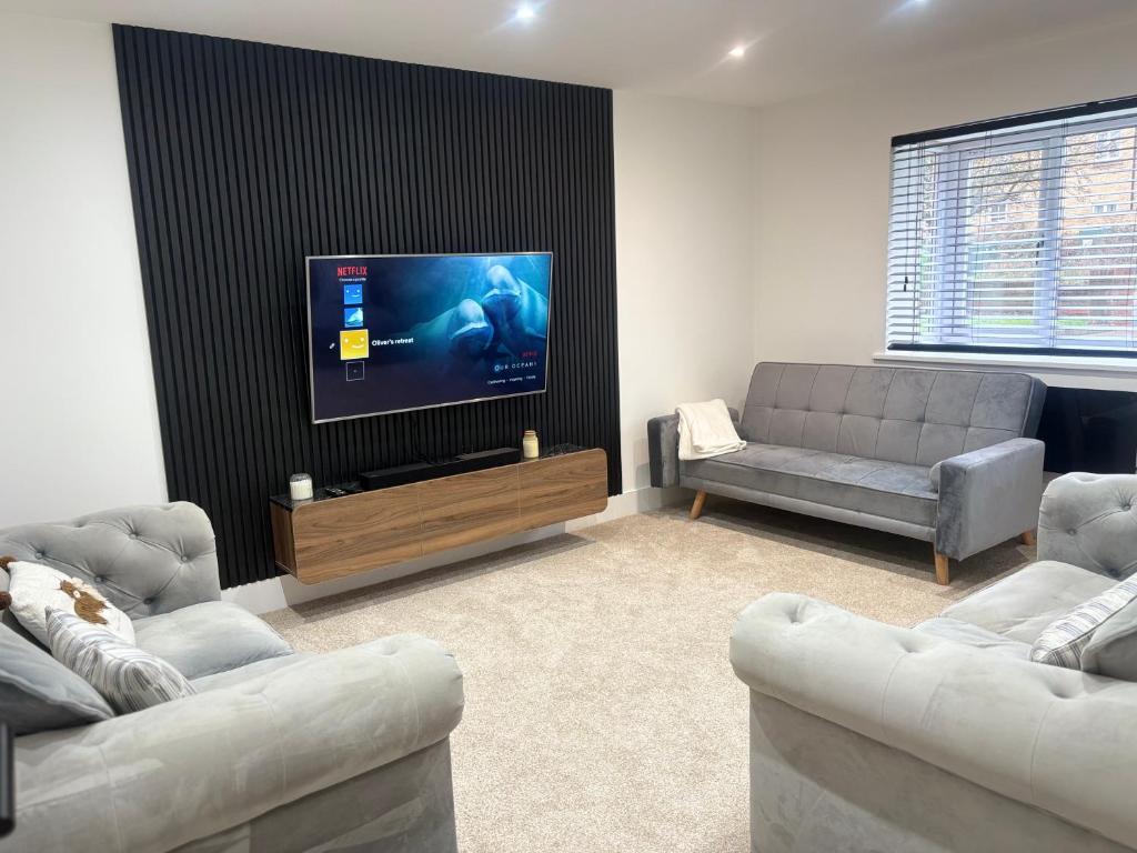 a living room with two couches and a flat screen tv at Olivers retreat in Braintree
