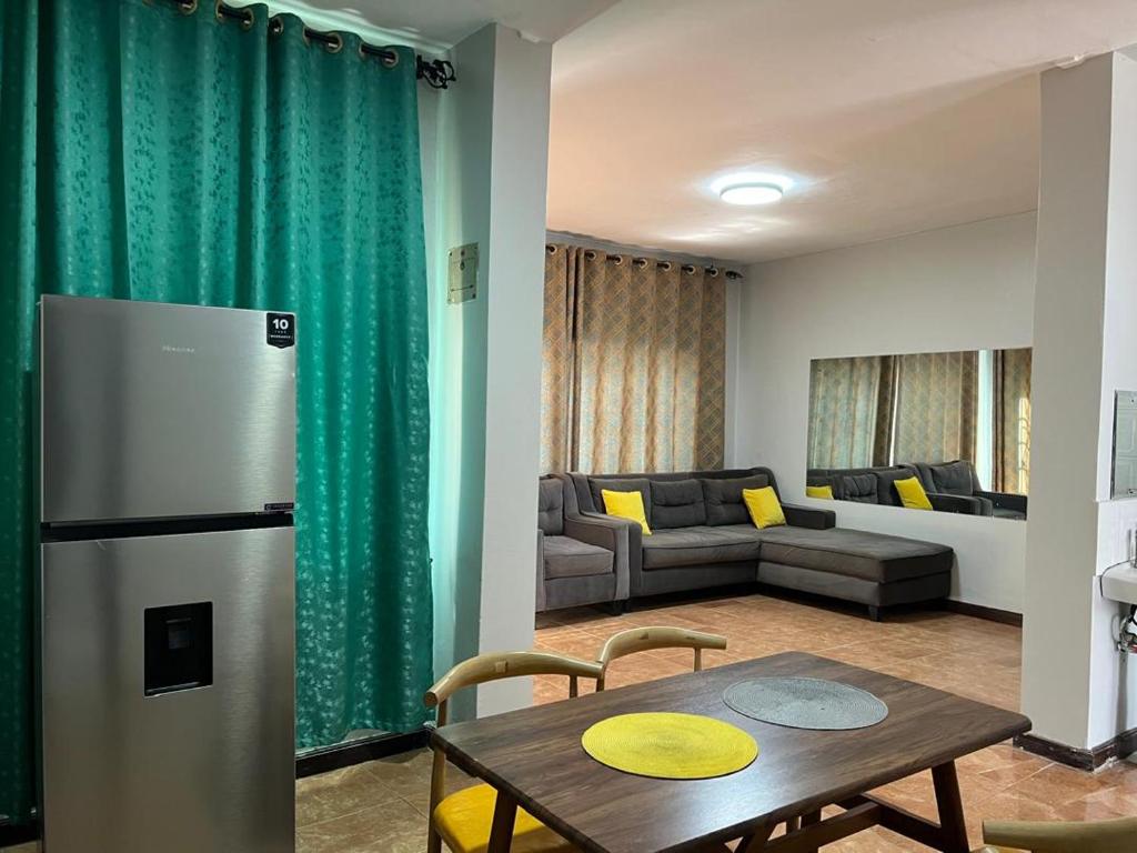 a kitchen and living room with a refrigerator and a table at Spacious one bedroom Bangalow -8E3 in Kampala
