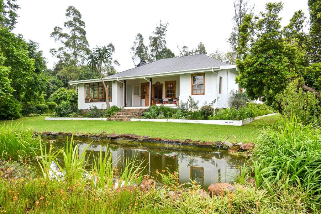a house with a pond in front of it at Burnside Lodge in Balgowan