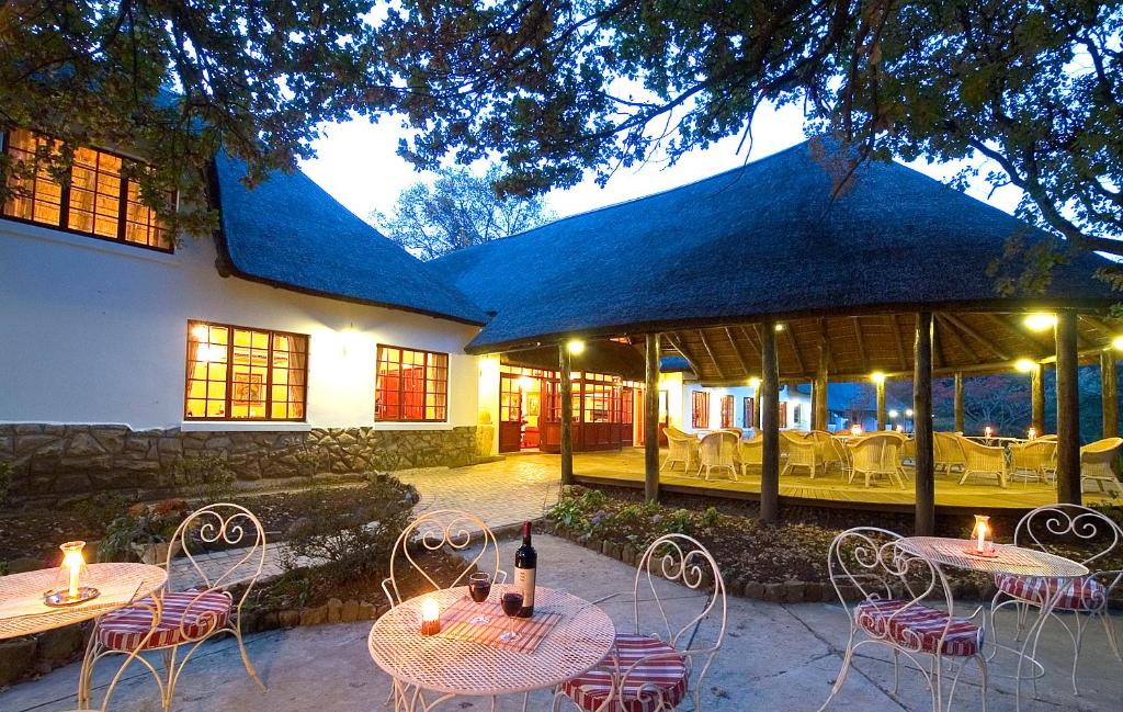 a patio area with tables, chairs and umbrellas at Hogsback Arminel Hotel in Hogsback