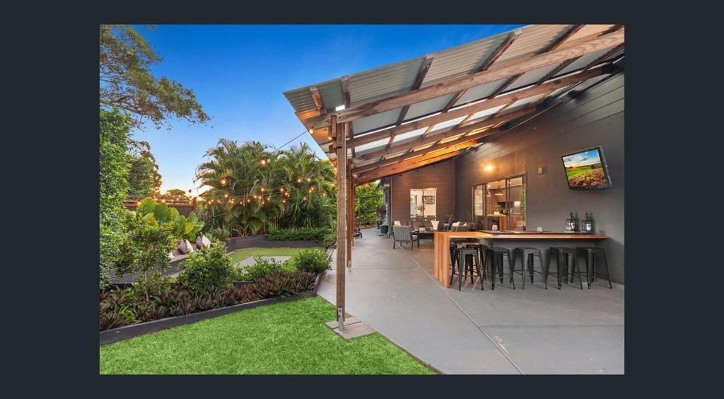 an outdoor entertaining area with a wooden pergola at Between Trees and Tide in Torquay