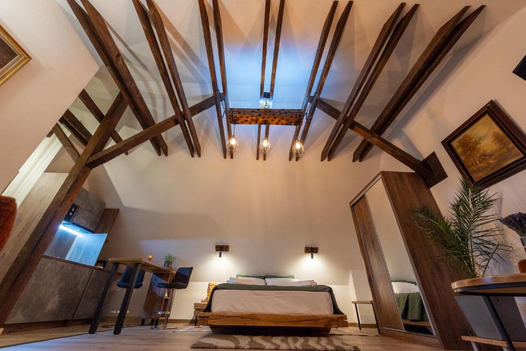a bedroom with a bed and a ceiling with beams at DIM Studio in Braşov