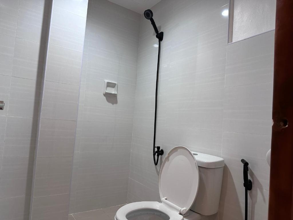 a white bathroom with a toilet and a shower at Capitol Tourist Inn 2026 in Cebu City