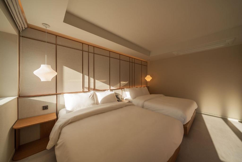 a hotel room with two beds with white sheets at 신북 온심재 in Sajŏng-dong