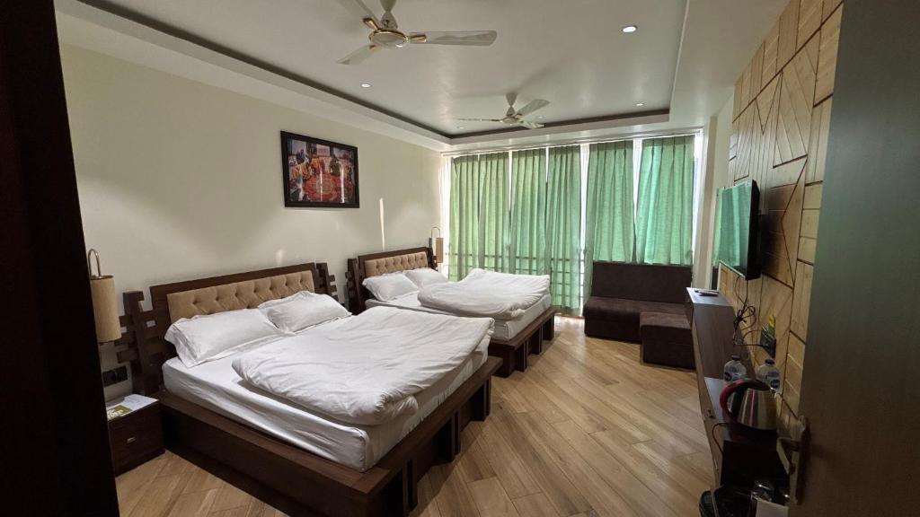 a bedroom with two beds and a television in it at Hotel Buransh in Haldwāni