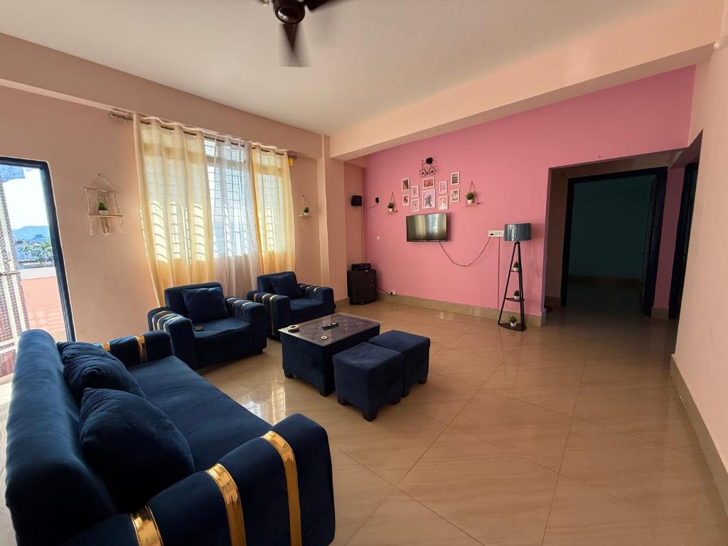 a living room with blue couches and a pink wall at Gray Haven Homestay in Guwahati