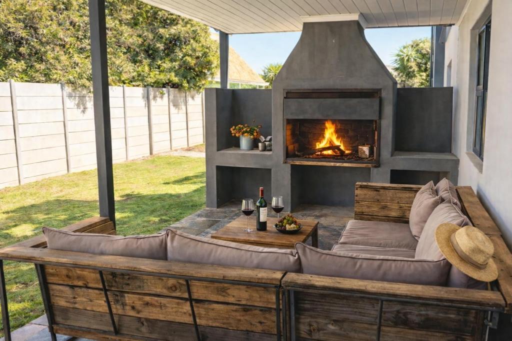 an outdoor seating area with a fireplace in a yard at Van Temp Beach House in Britannia Bay
