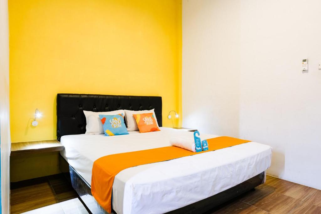 a bedroom with a large bed with an orange wall at Sans Salmas Mojokerto in Kranggan