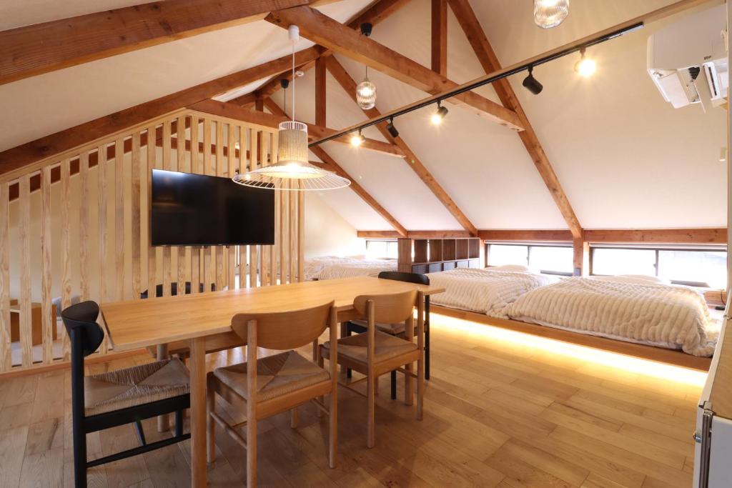 a dining room with a wooden table and a bed at Kurasako Onsen Sakura in Minamioguni