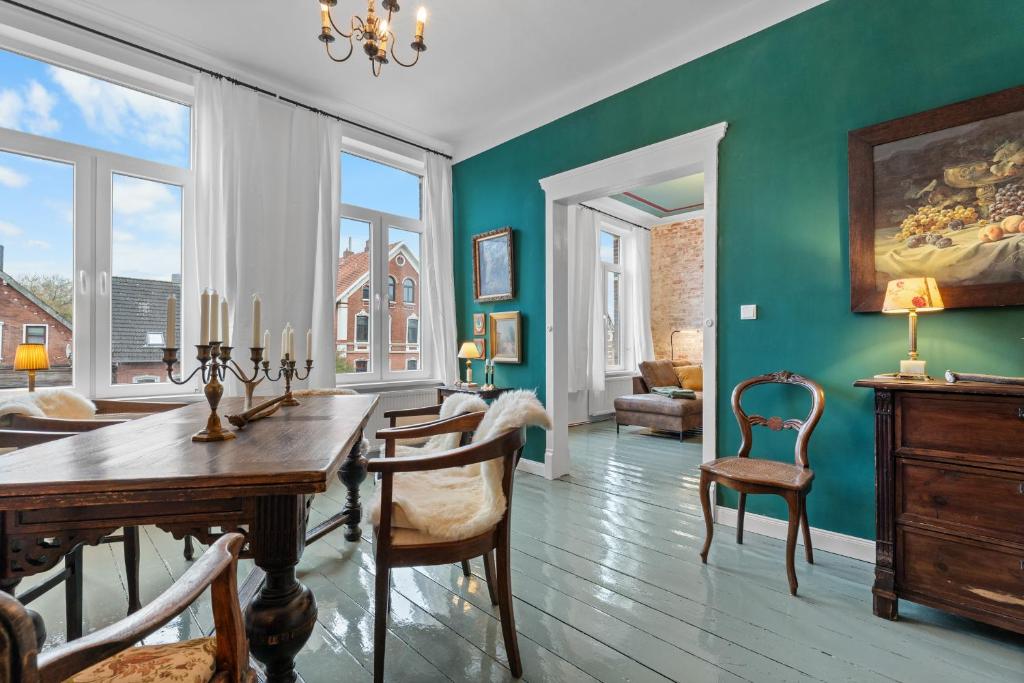 a dining room with green walls and a table and chairs at BELETAGE in Emden