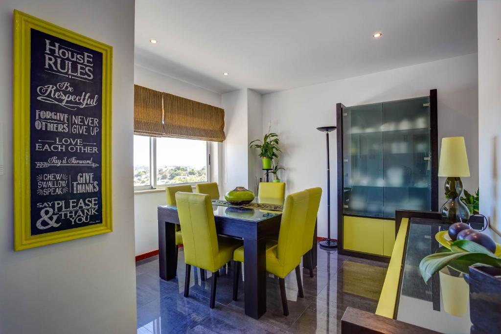 a dining room with a table and yellow chairs at Vila Cantinho Algarvio Vista Rio in Ferragudo