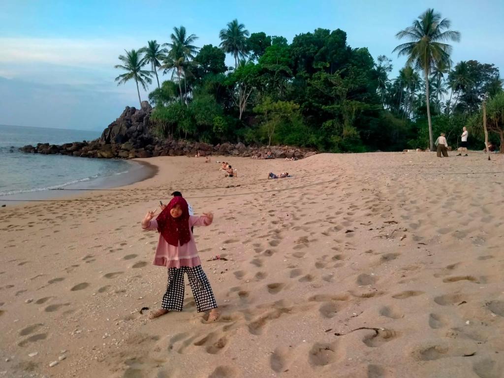 a girl standing on a beach with footprints in the sand at Lanta Beautiful beach house in Ko Lanta