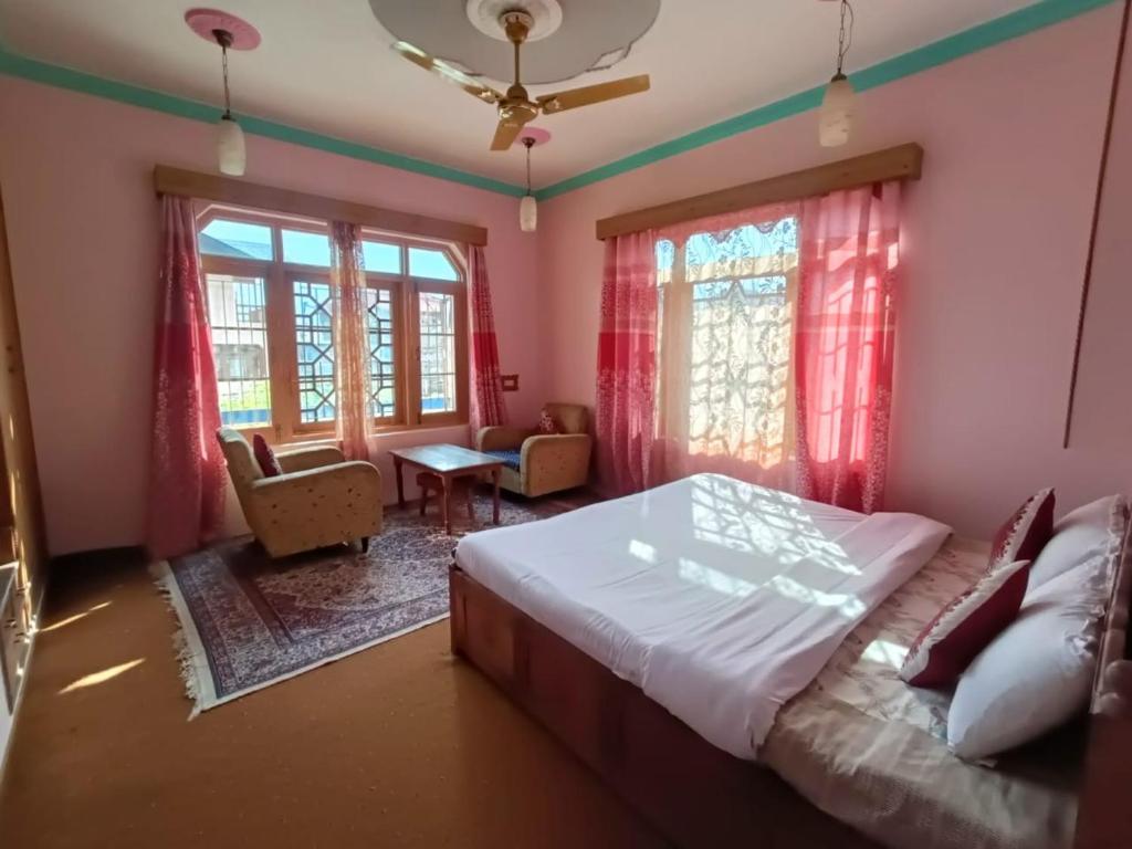 a bedroom with a bed and a chair and windows at Inayat hotel in Srinagar