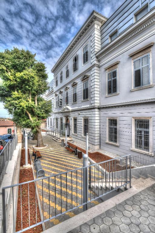 a large white building with stairs in front of it at SC Pula Rooms & Studio in Pula