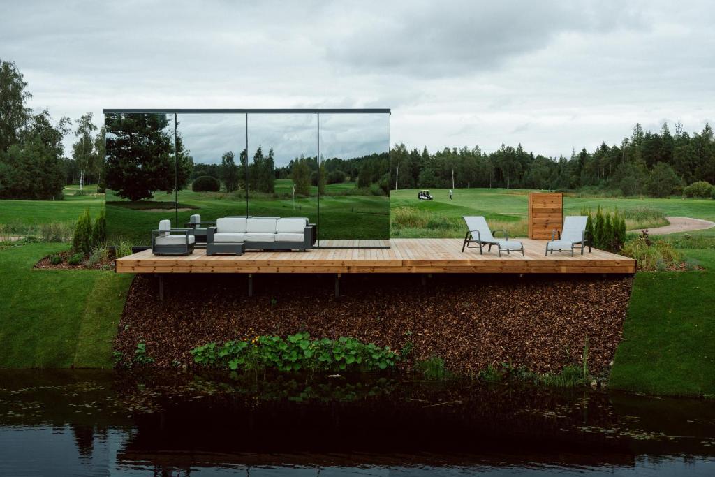 a deck with a couch and chairs on the water at CR x Rae Golf in Suuresta