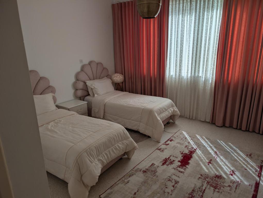 a bedroom with two beds and red curtains at Elegant Double Room in Abu Dhabi