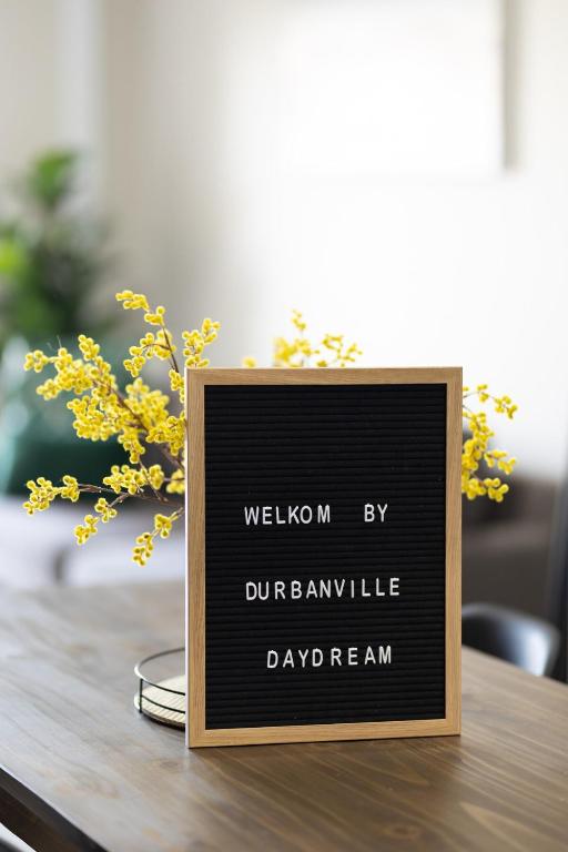 a sign sitting on top of a table with yellow flowers at Durbanville Daydream in Durbanville