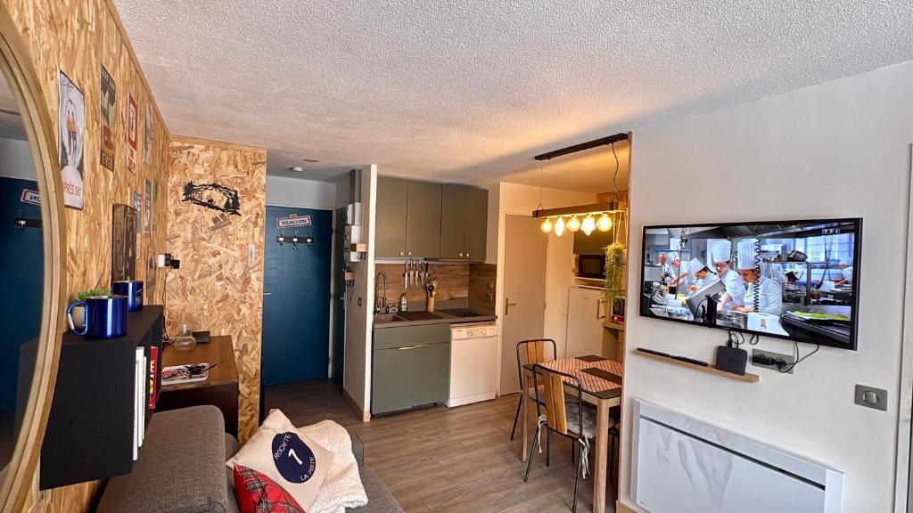 a living room with a television and a kitchen at les Loulous Réallon in Réallon
