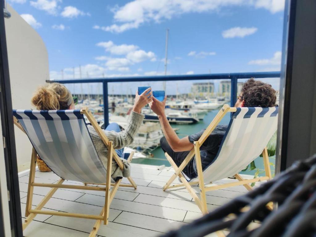 two people sitting in chairs on a balcony taking a picture of a boat at Tiny float home Brighton in Brighton & Hove