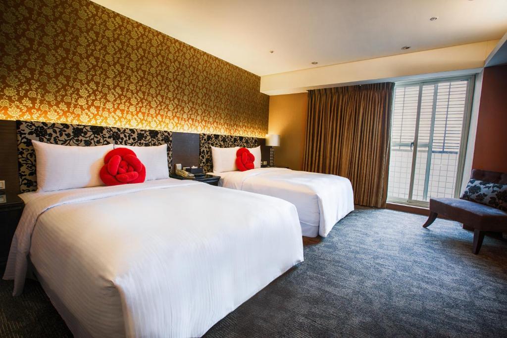 two beds in a hotel room with red pillows at Cai She Hotel in Taipei