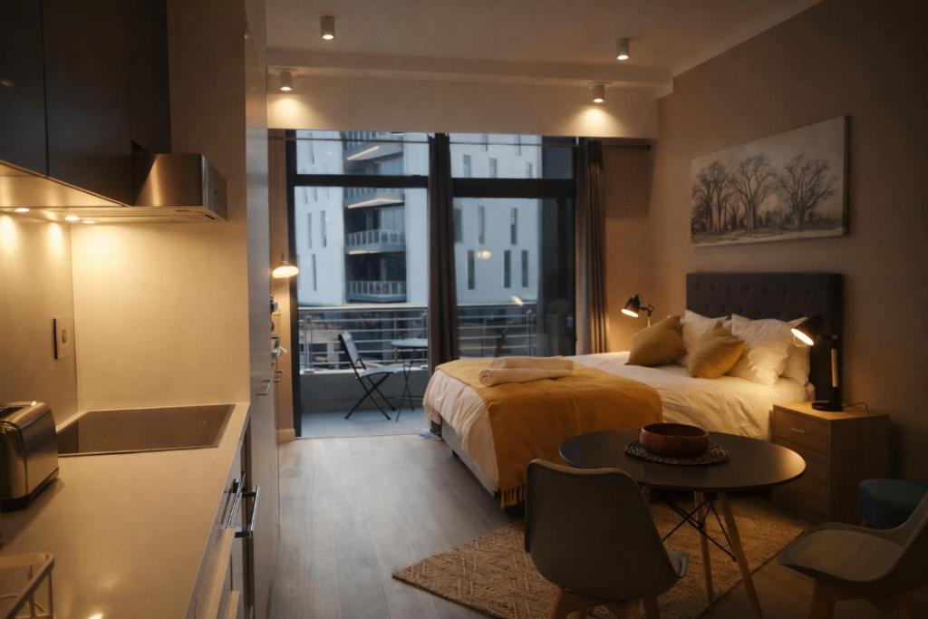 a bedroom with a bed and a table and a kitchen at Menlyn Apartment - Studio in Pretoria