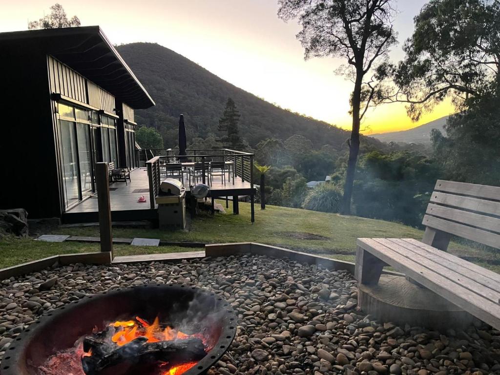 a fire pit and a bench next to a house at Sunset View House - Rustic Outdoor Bathhouse, Walk to Town in Warburton