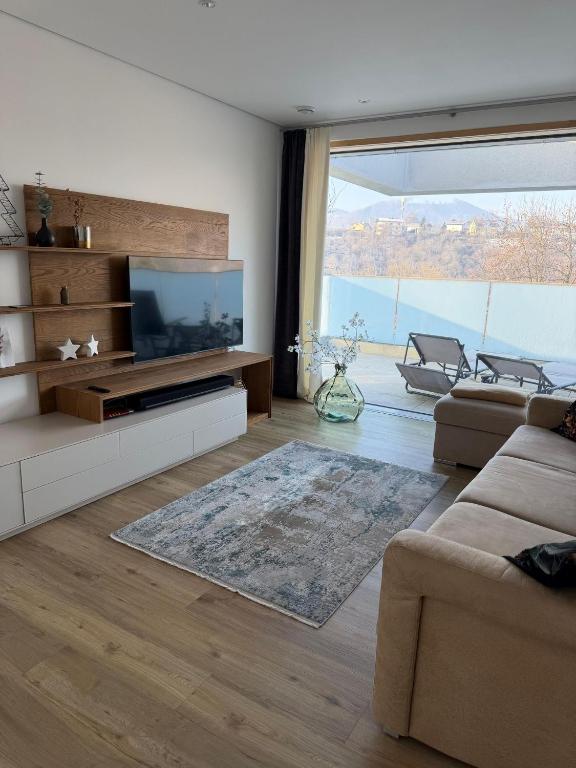 a living room with a television and a large window at Traunseeloft in Gmunden