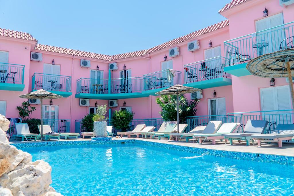 a swimming pool in front of a pink building at Maui Poolside Studios in Laganas