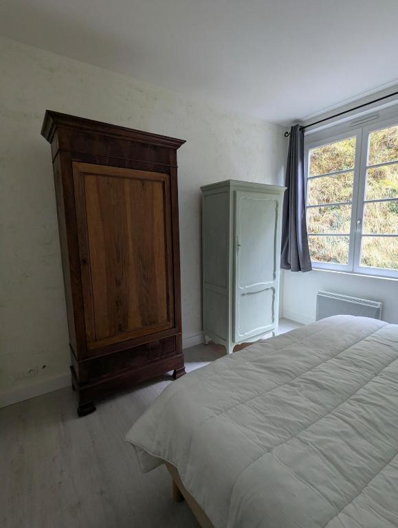 a bedroom with a bed and a cabinet and a window at Logement charmant à la montagne in Eaux-Bonnes