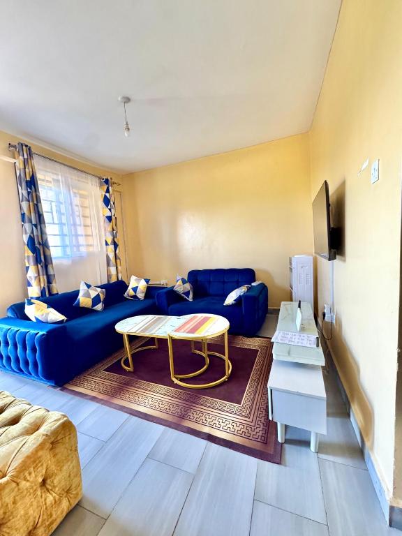 a living room with a blue couch and a table at Airport Bliss House in Kisumu