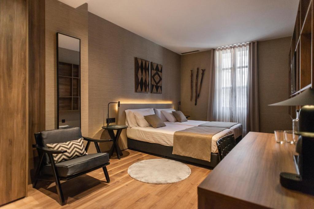 a bedroom with a bed and a chair at Blanq Gran vía in Valencia
