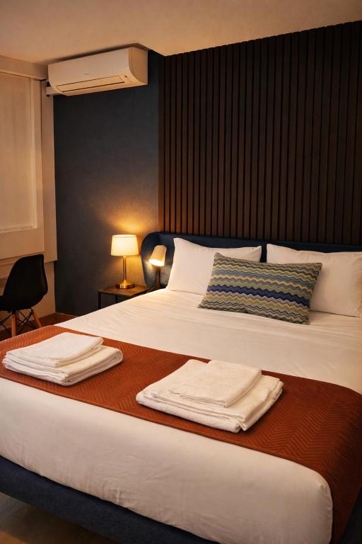 a bedroom with a large bed with towels on it at Marinha Garden Inn - AL in Marinha Grande