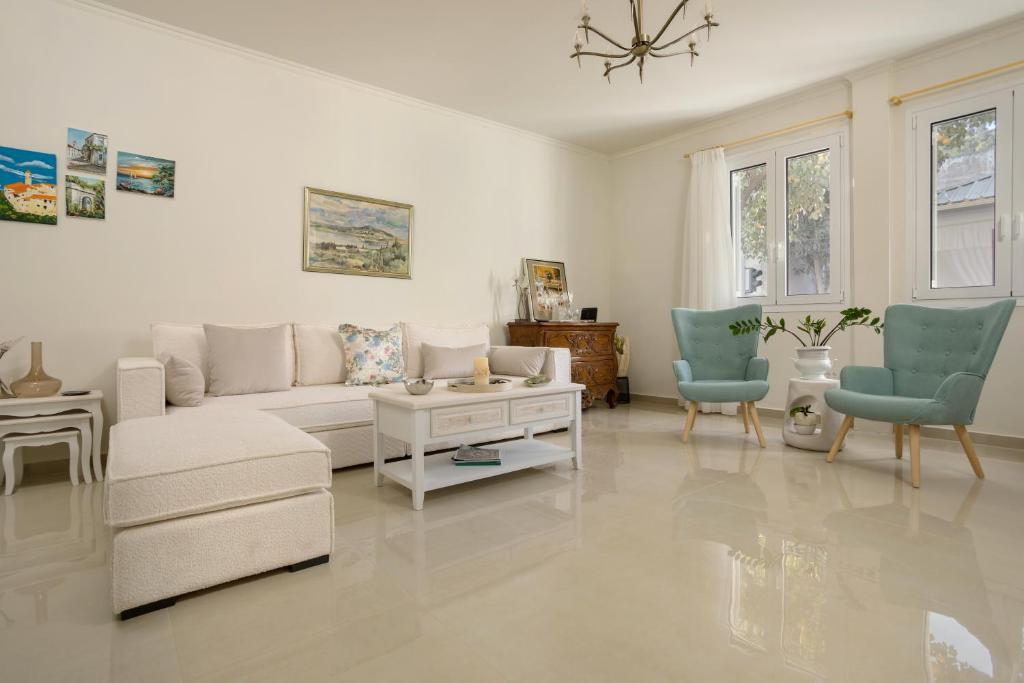 a living room with a white couch and blue chairs at Athenais Two Storey House in Zakynthos