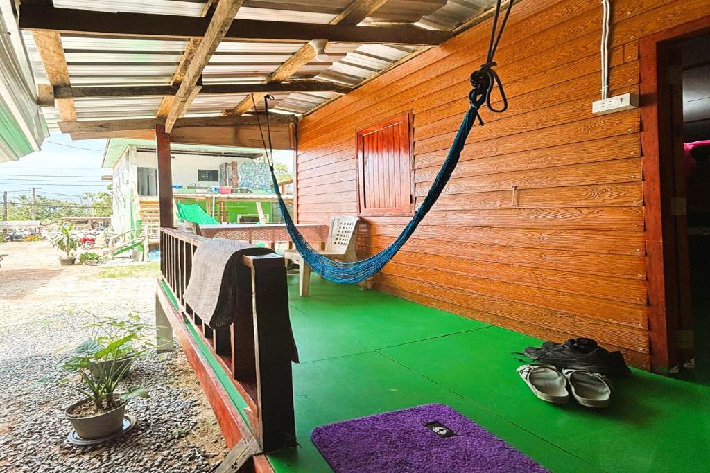 a porch with a hammock and shoes on the floor at I Daa Pra-ea Guesthouse in Phra Ae beach