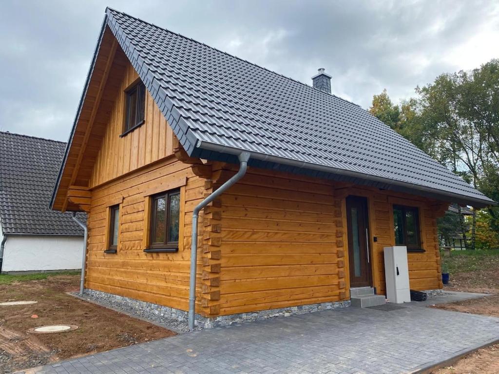 a large wooden cabin with a black roof at Bosnest Nr 176 in Frankenau