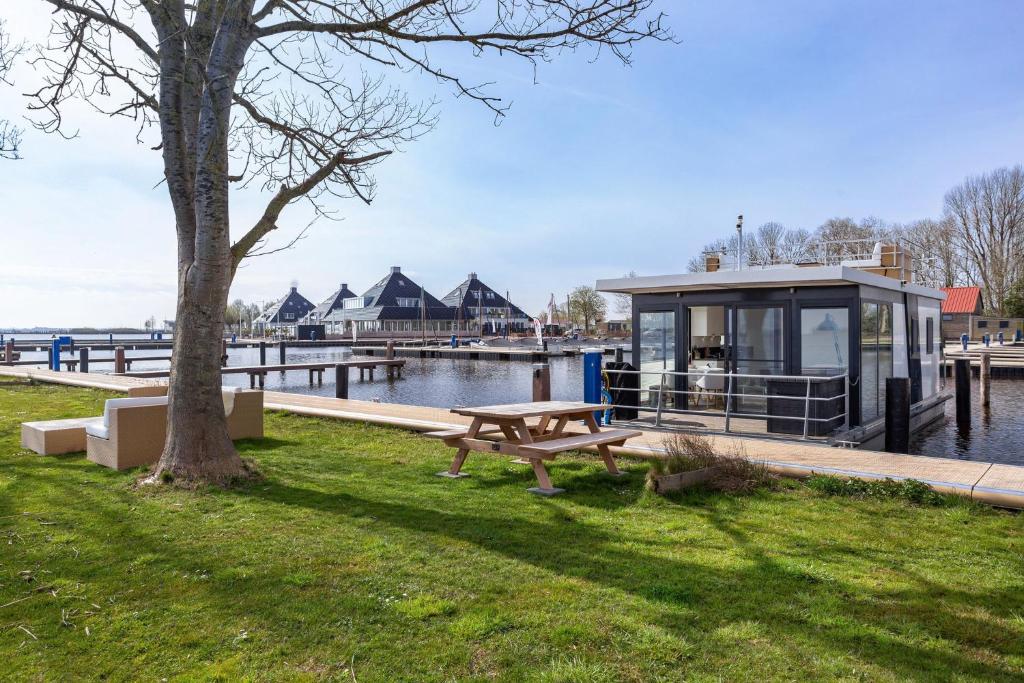 a building with a picnic table next to the water at Welcome in - Houseboat Agua Dolce met tuin, Paviljoenwei 4, Sneek - Offingawier in Offingawier