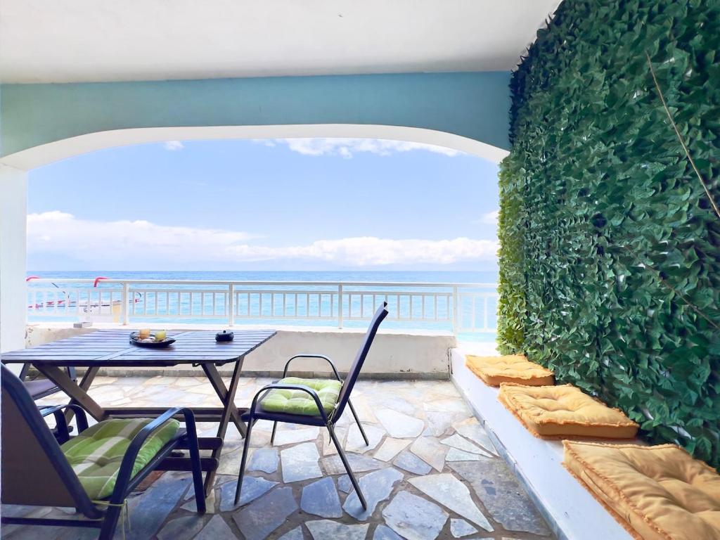 a patio with a table and chairs and the ocean at Beachfront summer house in Derveni