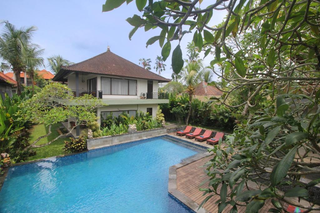 a swimming pool in front of a villa at Putri Ayu Cottages in Ubud
