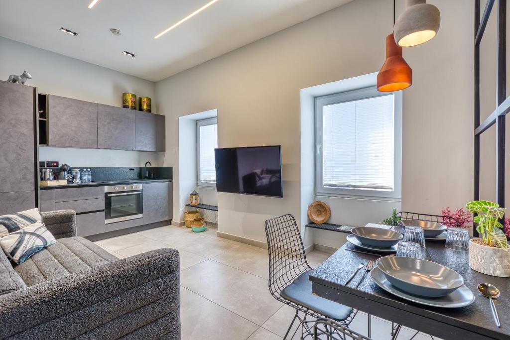 a kitchen and living room with a table and chairs at Stylish 1-Bedroom Apartment Just 5 Minutes from Valletta by Ferry in Mosta