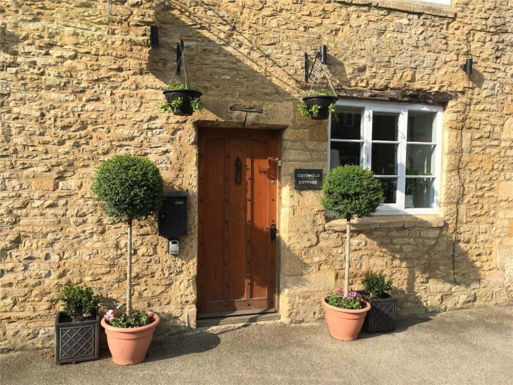 a stone building with two potted plants in front of a door at Cotswold Cottage Guest House in Stow on the Wold