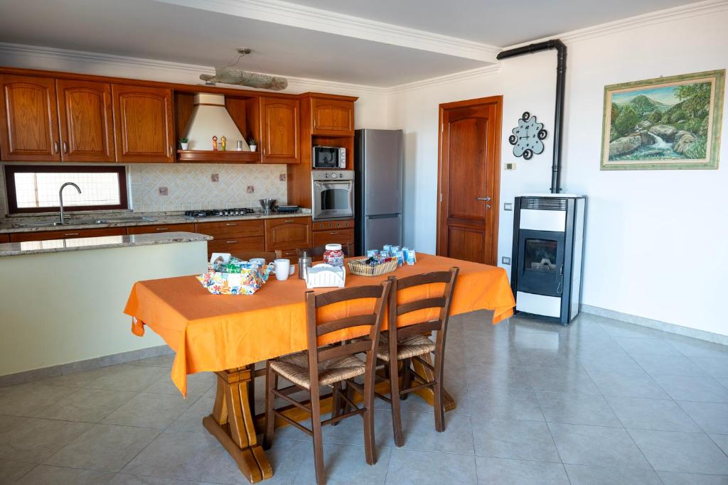 a kitchen with a table with chairs and a refrigerator at House Gennauara in Lanusei