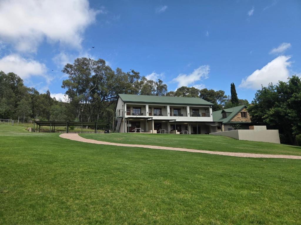 a house with a green roof on a grass field at Merino Guest Farm in Clarens