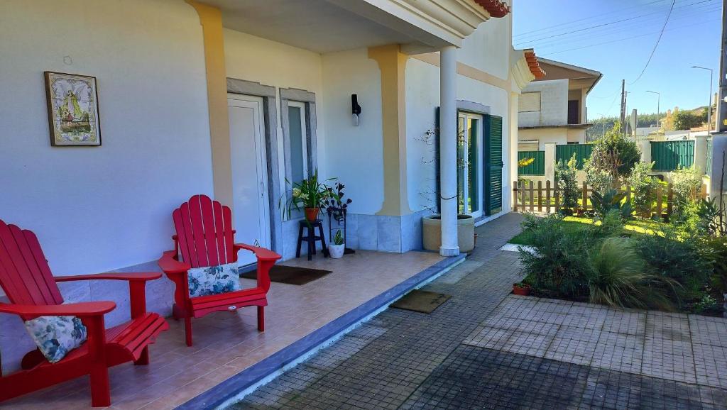 a patio with two red chairs on a house at Xixi Cama Bed & Breakfast in Bombardeira