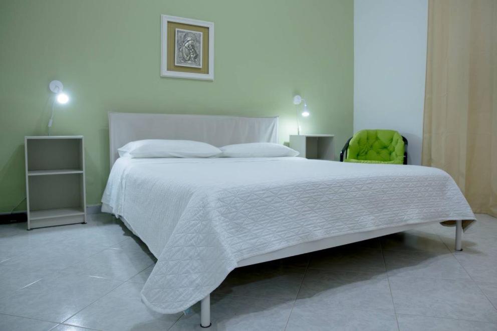 a bedroom with a large white bed and a green chair at Home's Vita in Trapani