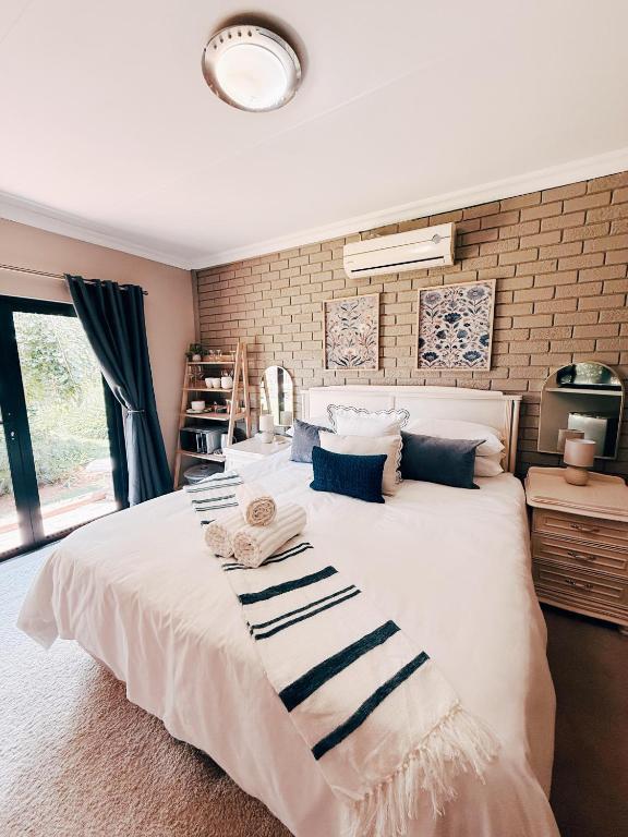 a bedroom with a large white bed and a brick wall at Peach Blossom Guesthouse in Welkom