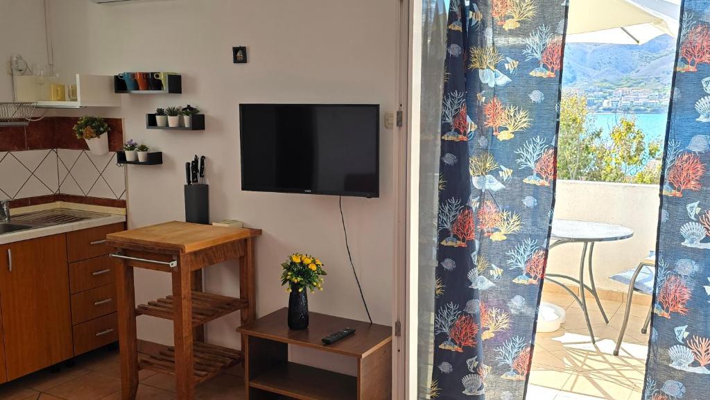 a kitchen with a tv on a wall with a table at Apartments Burcul Pag in Pag