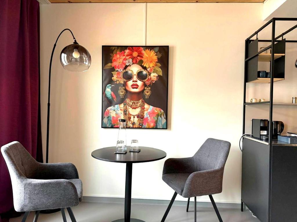 a table with two chairs and a painting of a woman at RS Boardinghouse Aparthotel mit Charme und Hotelservice in St. Gallen