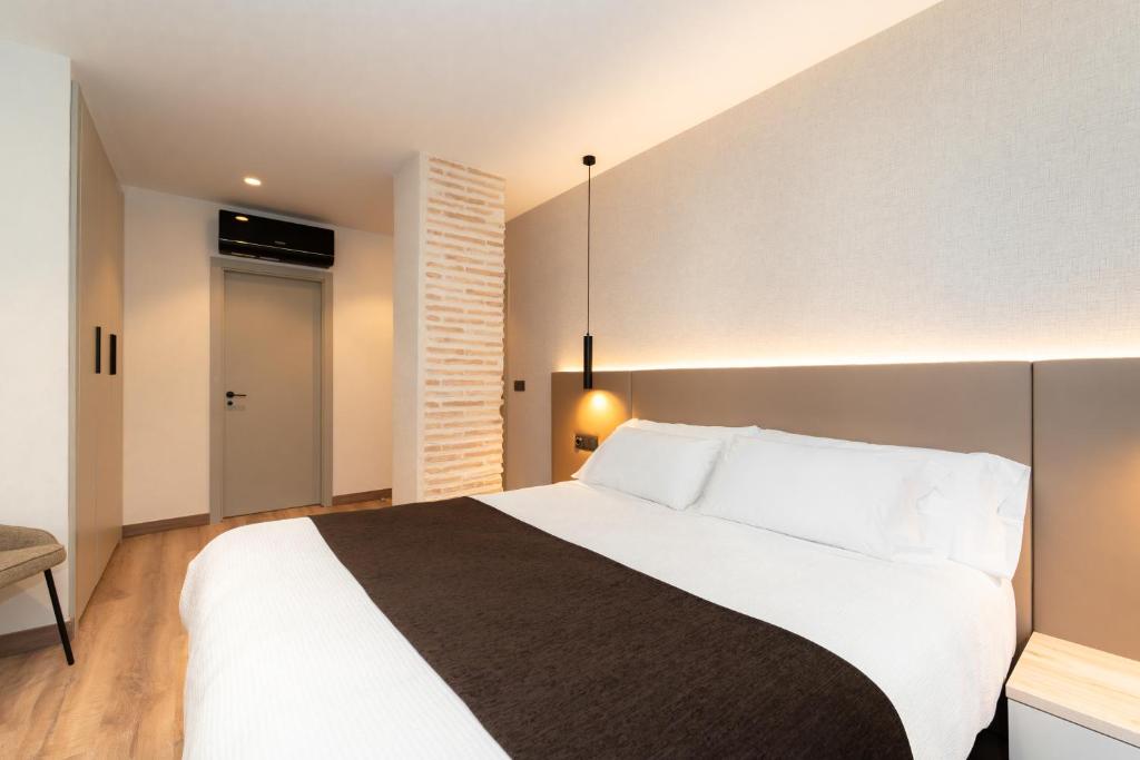 a bedroom with a large white bed with white pillows at L'Agora Rooms in Bocairent