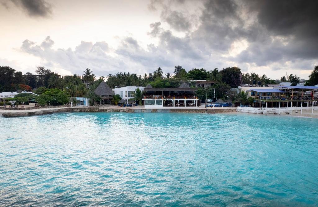 a large body of water with a resort in the background at Double A Nungwi Beach Hotel - Beach Front in Nungwi
