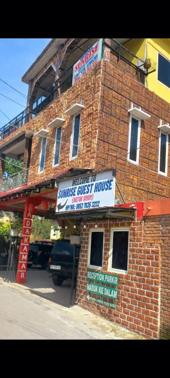 a brick building with a sign for a music guest house at WISMA SUNRISE GUEST HOUSE 10 minutes by walking to the big fruit market in Berastagi in Berastagi